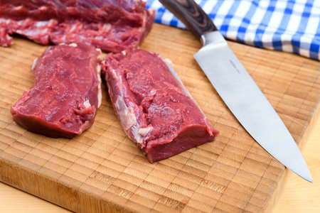 saddle of venison on wooden board with big knifeの写真素材