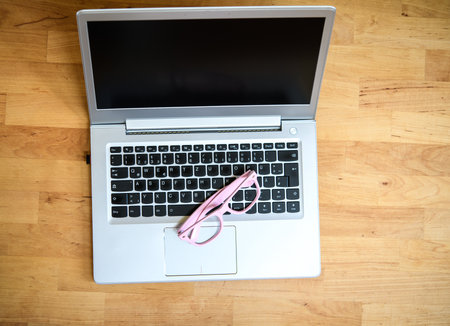 laptop with pink glasses on wooden groundの写真素材