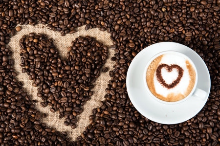 Cappuccino with heart on a lot of coffee beansの写真素材