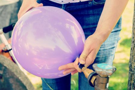 woman filling violet balloon with helium gasの写真素材