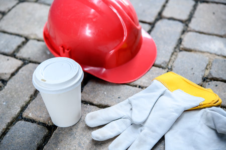 red helmet,coffee mug and work gloves on stonesの写真素材