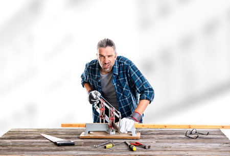 worker in blue plaid  shirt sawing woodの写真素材