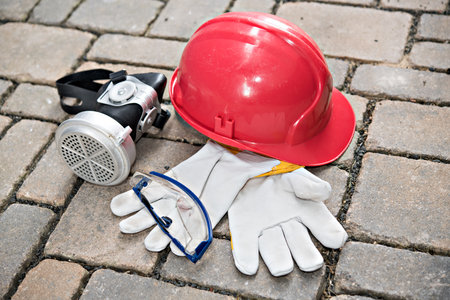 red helmet, respiratory mask,goggles and work gloves on stone groundの写真素材