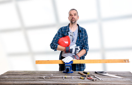 worker in blue plaid  shirt with red helmet on workbench の写真素材