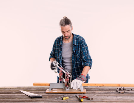 worker in blue plaid  shirt sawing woodの写真素材