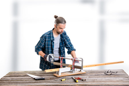 worker in blue plaid  shirt sawing woodの写真素材