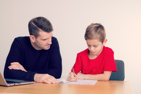 father helping his son with homework at tableの写真素材