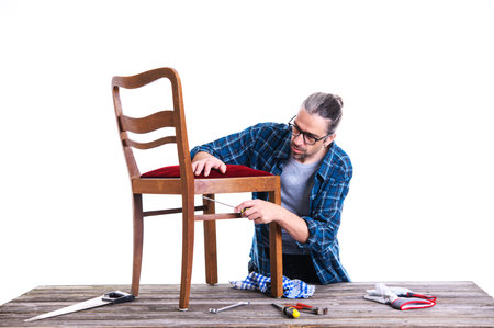 worker in blue plaid  shirt repair old chairの写真素材