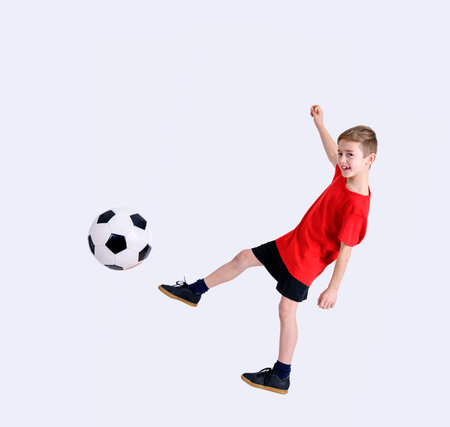 boy in red shirt with soccer ball in front of white backgroundの写真素材