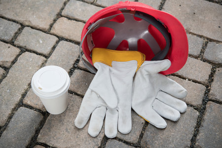 red helmet,coffee mug and work gloves on stonesの写真素材