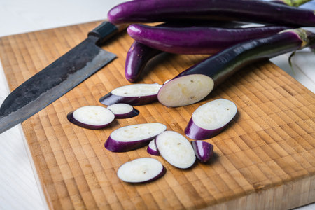 japanese eggplant on wooden board with cooking knife and pak choi saladの写真素材