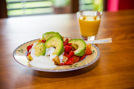 plate with fried vegetables and row avocado with orange juice  on wooden groundの写真素材