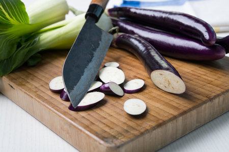japanese eggplant on wooden board with cooking knife and pak choi saladの写真素材