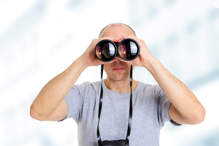 young man in gray shirt looking  through a binocularsの写真素材