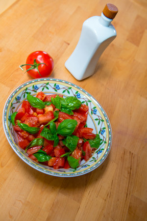 summer salad with tomato basil and oil bottle on wooden groundの写真素材