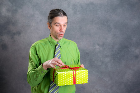 young  man in green shirt and necktie with green gift box is surprisedの写真素材