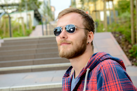 young bearded man with sunglasses in checkered shirt standing on stairsの写真素材