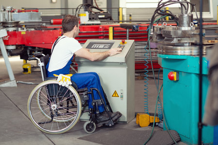 disabled worker in wheelchair in factory on the machineの写真素材