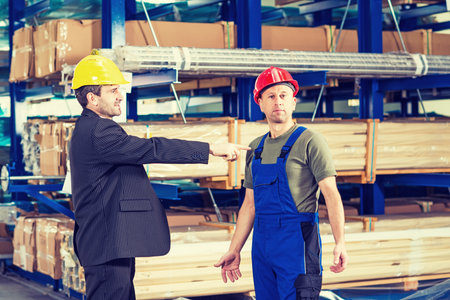 in the factory- boss pointing at worker in factoryの写真素材