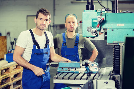 two worker in factory on work bench and machineの写真素材