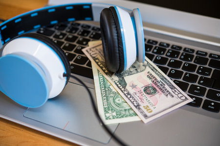 computer keyboard with headphones and dollar bank notesの写真素材