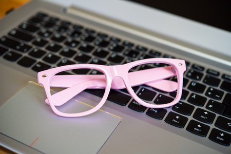 laptop with pink glasses on wooden groundの写真素材