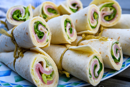 wraps with ham and salad on plateの写真素材