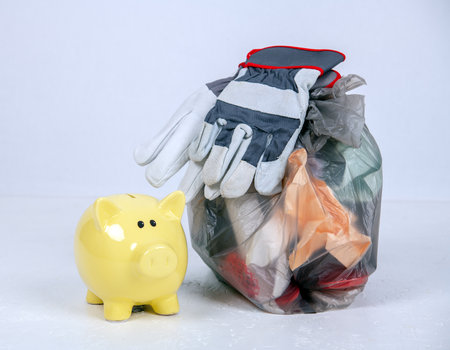 garbage bag with defferent content with yellow piggy bank and work glovesの写真素材