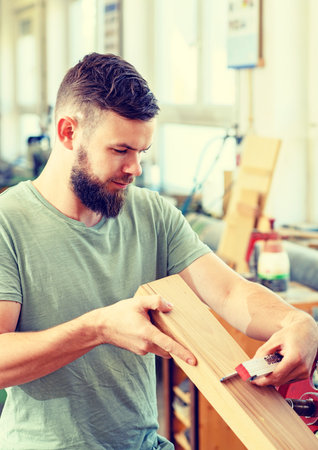 young worker with workpiece in a carpenter's workshopの写真素材