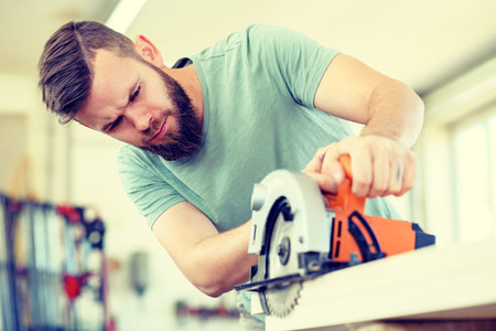 young worker with hand saw in a carpenter's workshopの写真素材