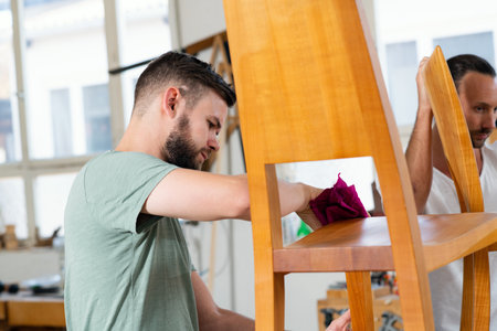 young worker with wooden chair in a carpenter's workshopの写真素材