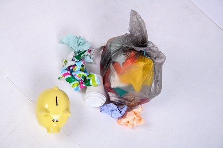 garbage bag with defferent content with yellow piggy bank and work glovesの写真素材