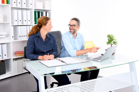 young businessman with piggy bank and businesswoman together in the officeの写真素材