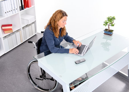 disabled businesswoman in wheelchair working  in the officeの写真素材