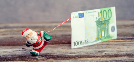 little Santa Claus pulling big euro banknoteの写真素材