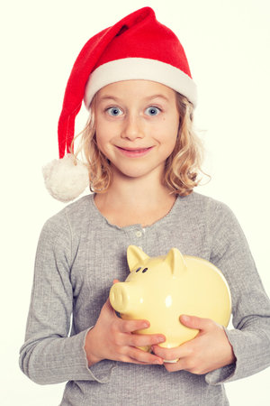 nice blond girl with Santa- cap and piggy bankの写真素材