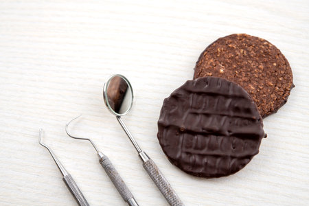 three different dental instruments and chocolate cookie on bright groundの写真素材