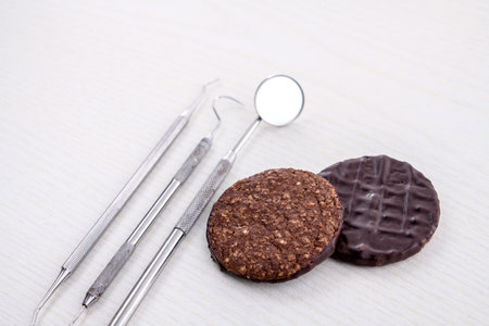 three different dental instruments and chocolate cookie on bright groundの写真素材