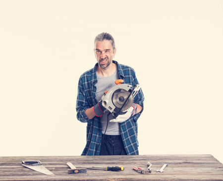 funny worker in blue plaid  shirt working with electric sawの写真素材