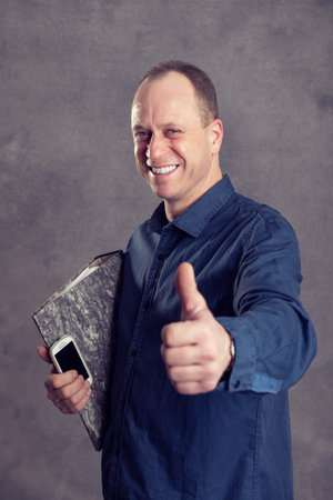 young businessman with folder,  phone and thumb upの写真素材