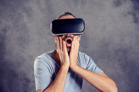 young man with virtual reality glasses looking surprisedの写真素材