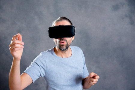 young man using virtual reality glasses and looking surprisedの写真素材