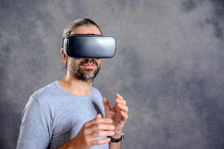young man using virtual reality glasses in front of gray backgroundの写真素材