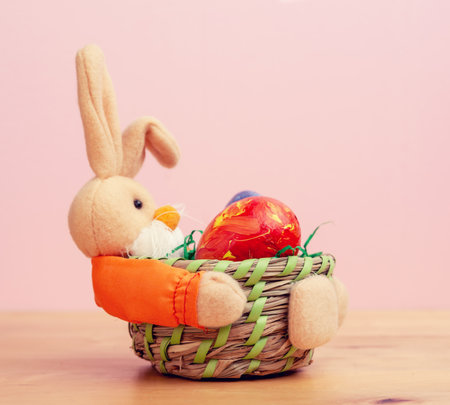 easter bunny in basket with egg in front of pink backgroundの写真素材