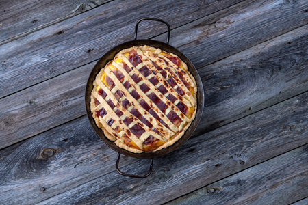 sweet pie in iron pan on wooden groundの写真素材