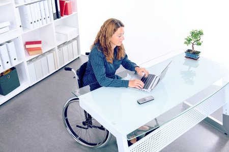 disabled businesswoman in wheelchair working  in the officeの写真素材