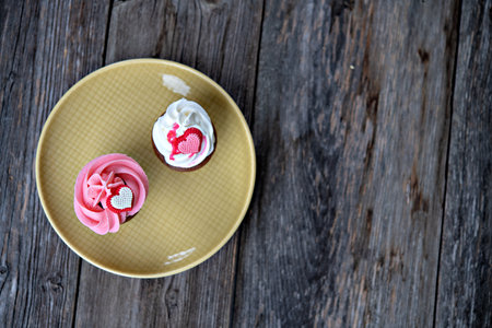 pink and white muffins on wooden ground whipping cream and heartの写真素材