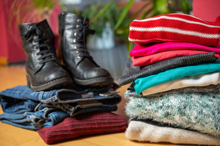 pile of second hand clothing and  shoes with computer on floor in living roomの写真素材