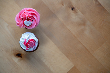 pink and white muffins on wooden ground whipping cream and heart in top viewの写真素材