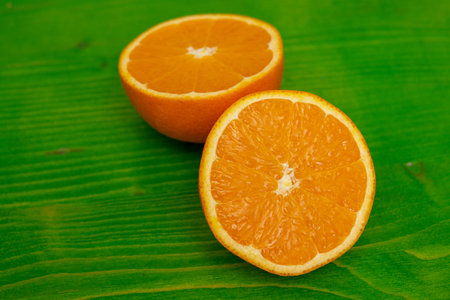 two halves of a ripe juicy orange on green groundの写真素材